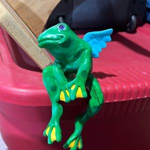 Winged frog sits and holds on